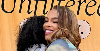 Two women hugging with a 'Unfiltered' background